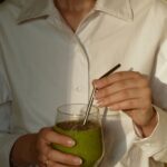 바쁜 일상 속 ‘웰니스 문화’, 작은 변화로 몸과 마음을 챙긴다 person in white button up shirt holding clear drinking glass with green liquid