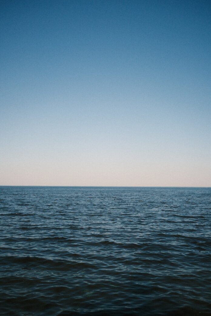 Blue ocean meets clear sky at horizon