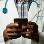 디지털 헬스케어, 손안의 건강관리 혁명 person wearing lavatory gown with green stethoscope on neck using phone while standing